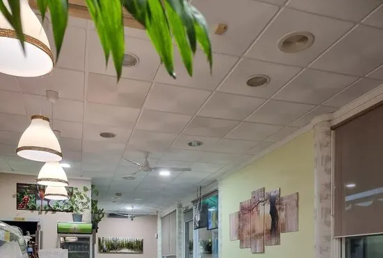 Interior del bar: barra de madera a la izquierda, lámparas blancas colgantes y mesas al fondo
